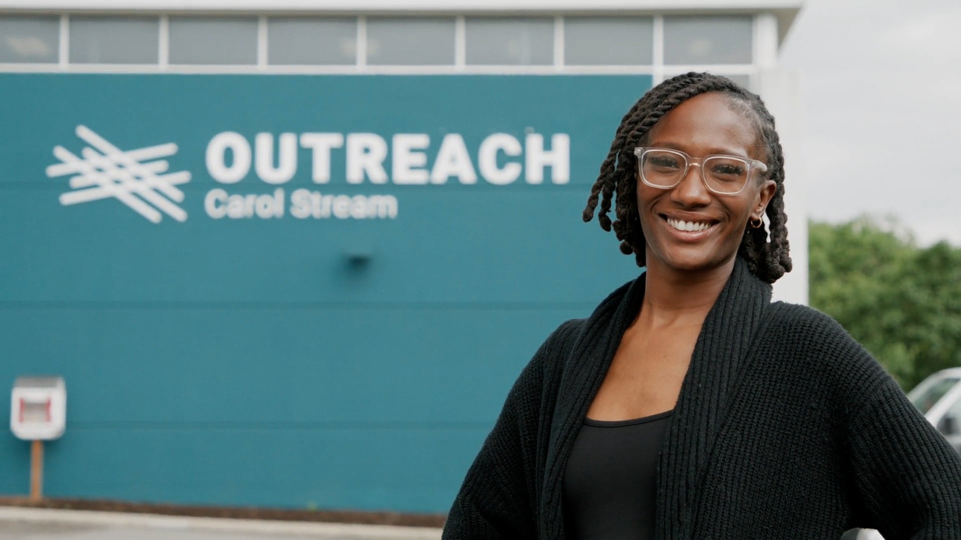 A smiling woman standing outside the Outreach Carol Stream building